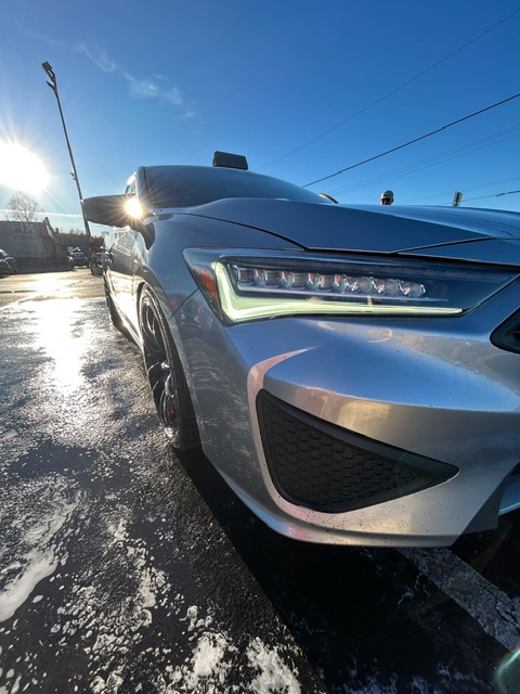 Silver Acura with polished headlight and paint catching the sunrise